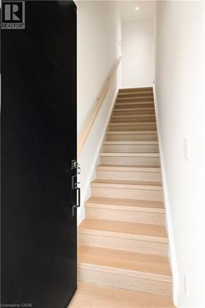 Kitchener apartment for rent - A staircase with wooden steps and a black door on the left.