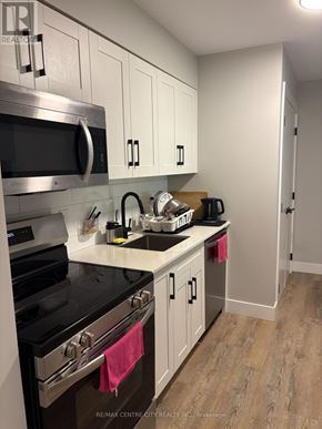 London South (South J) multi-family for rent - A kitchen with white cabinets and a black stove top.