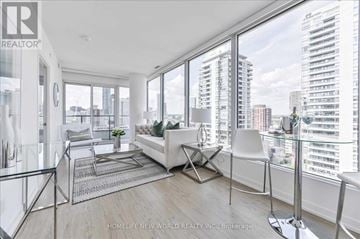 Toronto (Church-Yonge Corridor) condo for rent - A living room with a white sofa and a glass table with a city view through the window.