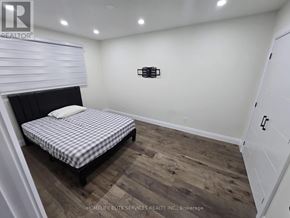 Toronto (Agincourt South-Malvern West) apartment for rent - A bedroom with a bed, wooden flooring, and a white wall.