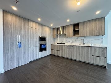 Surrey apartment for rent - A modern kitchen with wooden cabinets and a marble countertop.