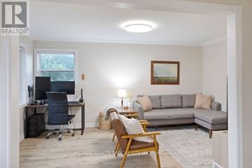 St. Catharines (Western Hill) apartment for rent - A living room with a grey couch, a black chair, a desk with a computer, and a painting on the wall.