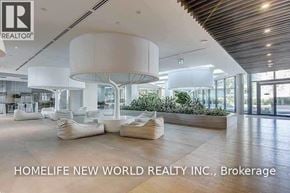 Toronto (Waterfront Communities) condo for rent - A modern interior space with a large white circular light fixture and a sign that reads "HOMELIFE NEW WORLD REALTY INC., Brokerage".