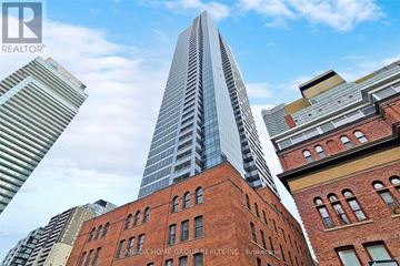Toronto (Bay Street Corridor) condo for rent - A tall skyscraper stands in front of a row of red brick buildings.