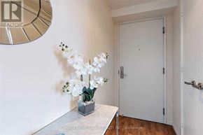 Toronto (Bay Street Corridor) condo for rent - A white door is closed in a room with a table and a vase of flowers.