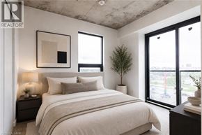 Brantford condo for rent - A bedroom with a large bed, a nightstand with a lamp, and a framed picture on the wall.