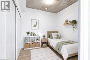 Brantford condo for rent - A bedroom with a bed, a nightstand, and a shelf with plants and books.