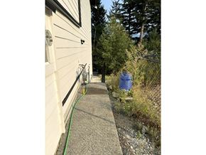 Chilliwack apartment for rent - A blue barrel is on the ground next to a white house.