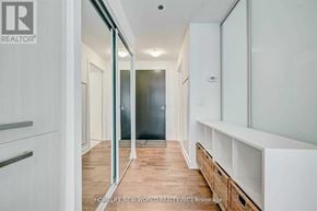 Toronto (Kensington-Chinatown) condo for rent - A hallway with a glass door leading to a bathroom and a wooden floor.