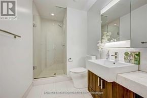 Toronto (Kensington-Chinatown) condo for rent - A white bathroom with a glass shower stall and a white toilet.