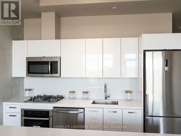 Toronto (Waterfront Communities) condo for rent - A kitchen with white cabinets and a stainless steel refrigerator.