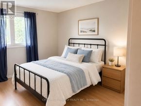 Ottawa townhouse for rent - A bedroom with a bed, nightstand, and a window with blue curtains.
