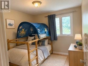 Ottawa townhouse for rent - A bedroom with a bed, nightstand, and window.