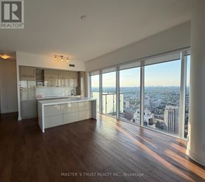 Toronto (Bay Street Corridor) condo for rent - A spacious, well-lit room with wooden floors and a large window offering a city view.