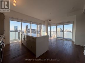 Toronto (Bay Street Corridor) condo for rent - A spacious room with wooden floors and large windows overlooking a cityscape.