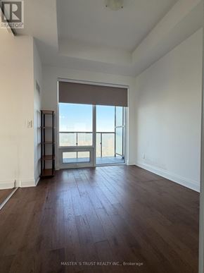 Toronto (Bay Street Corridor) condo for rent - A room with wooden floors and a large window with a view of the city.