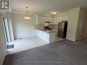 Brantford townhouse for rent - A spacious kitchen area with white cabinets and a central island.