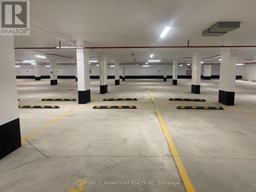 Clarington (Bowmanville) condo for rent - A spacious parking garage with multiple parking spaces and yellow lines on the floor.