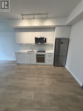 Toronto (Henry Farm) condo for rent - A kitchen with white cabinets and a wooden floor.