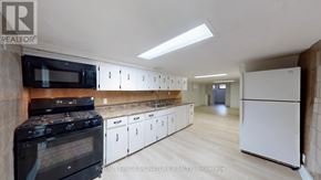 Toronto (Trinity-Bellwoods) apartment for rent - A kitchen with white cabinets and a black stove top oven.