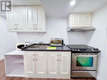 Markham (Berczy) apartment for rent - A kitchen with white cabinets and a black countertop.