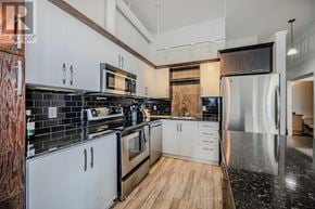Kitchener condo for rent - A modern kitchen with white cabinets and black countertops.