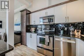 Kitchener condo for rent - A modern kitchen with stainless steel appliances and white cabinets.