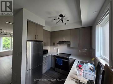 Toronto (New Toronto) townhouse for rent - A kitchen with a refrigerator, oven, and a dining table with chairs.