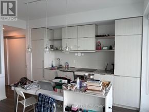 Toronto (Church-Yonge Corridor) condo for rent - A kitchen with white cabinets and a table with a laptop and various items on it.