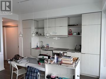 Toronto (Church-Yonge Corridor) condo for rent - A kitchen with white cabinets and a table with a laptop and various items on it.