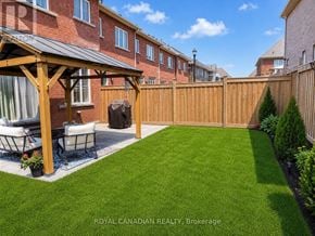 Clarington (Bowmanville) townhouse for rent - A backyard with a wooden deck and a lawn.