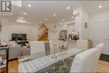 Vaughan (Maple) townhouse for rent - A modern living room with a glass table and a staircase in the background.