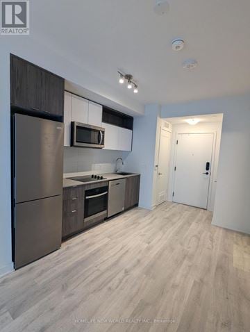Toronto (Waterfront Communities) condo for rent - A modern kitchen with a refrigerator, microwave, oven, and cabinets.