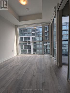 Toronto (Waterfront Communities) condo for rent - A room with a large window overlooking a building with many windows.