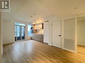 Toronto (Moss Park) condo for rent - A spacious room with wooden flooring and white walls.