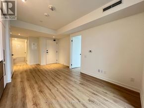 Toronto (Moss Park) condo for rent - A spacious room with wooden flooring and white walls.