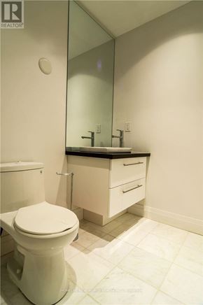 Toronto (Willowdale East) condo for rent - A white toilet sits in a bathroom next to a sink and mirror.