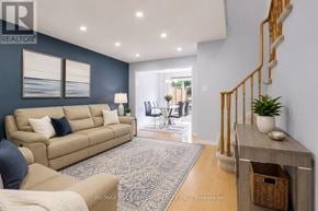 Burlington (Uptown) apartment for rent - A living room with a beige couch, a grey rug, and a wooden staircase.