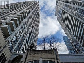 Toronto (Bay Street Corridor) condo for rent - A view of a cityscape with tall buildings and a blue sky with clouds.