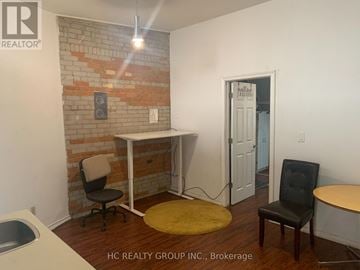Toronto (Moss Park) triplex for rent - A room with a brick wall and a white desk with a chair.