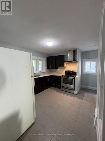 London East (East B) apartment for rent - A kitchen with a white refrigerator, black cabinets, and a stove top oven.