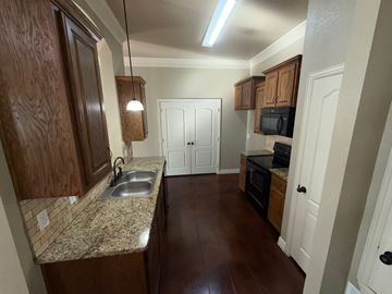 Temple triplex for rent - A kitchen with brown cabinets and a granite countertop.