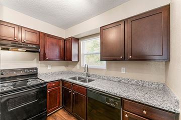 Avondale Estates apartment for rent - A kitchen with a black stove top oven and wooden cabinets.