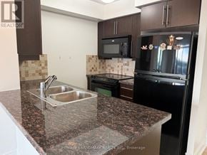 Toronto (Newtonbrook West) condo for rent - A kitchen with granite countertops and black appliances.