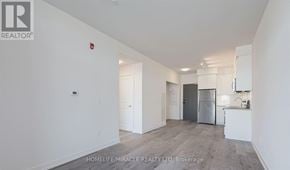 Whitby (Pringle Creek) condo for rent - A spacious, empty room with a kitchen area in the background.