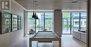 Toronto (Waterfront Communities) condo for rent - A modern living room with a pool table and a view of the city.