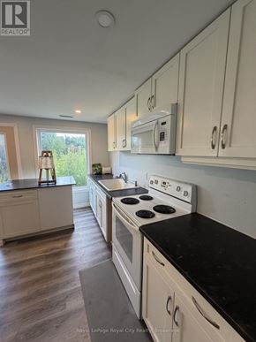 Guelph (Pineridge/Westminster Woods) apartment for rent - A kitchen with white cabinets and a black countertop.