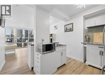 Vancouver apartment for rent - A kitchen with white cabinets and a large window overlooking the city.