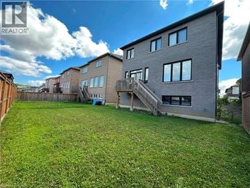 Ancaster apartment for rent - A well-maintained lawn in front of a grey building with a blue door.