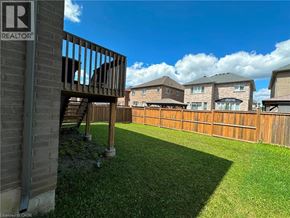 Ancaster apartment for rent - A realtor sign is on a building in front of a fenced yard.